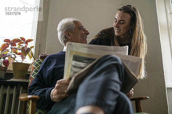 Glückliche junge Frau und älterer Mann mit Zeitung zu Hause