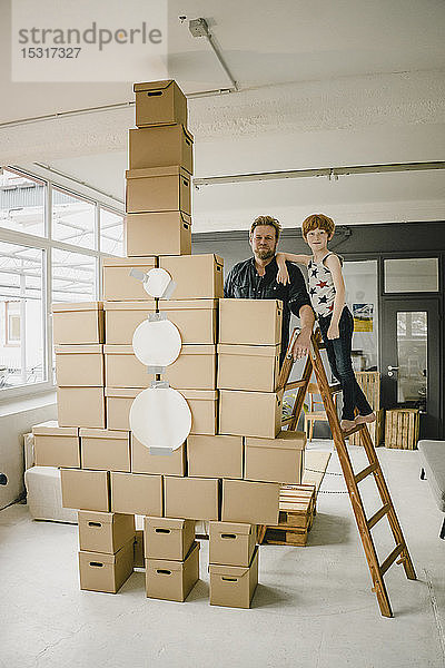 Porträt von Vater und Sohn beim gemeinsamen Spielen mit einer aus Pappkartons gebauten Rakete