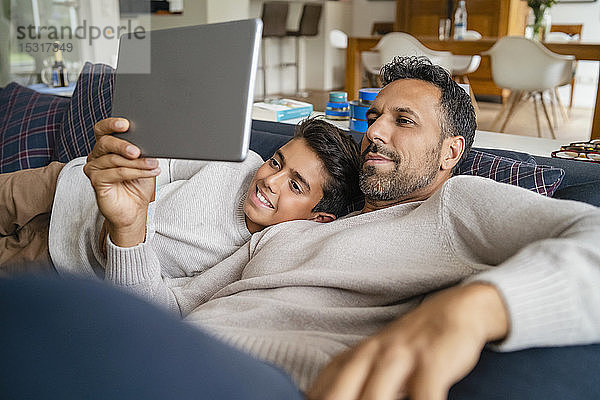 Glückliche Vater und Sohn benutzen Tablette auf der Couch im Wohnzimmer
