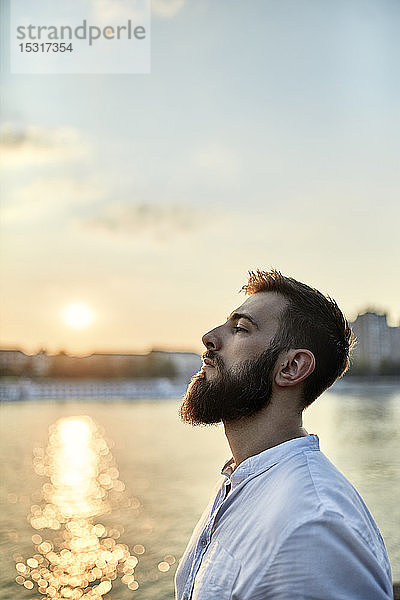 Bildnis eines Mannes mit Bart an einem Flussufer bei Sonnenuntergang