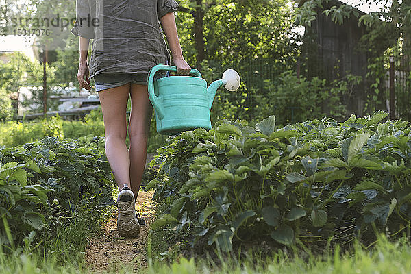 Nahaufnahme einer Frau mit Gießkanne beim Spaziergang im Garten