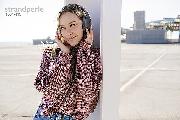 Porträt einer lächelnden jungen Frau  die mit drahtlosen Kopfhörern Musik hört  Barcelona  Spanien
