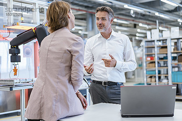 Geschäftsmann und Geschäftsfrau im Gespräch in einer modernen Fabrikhalle