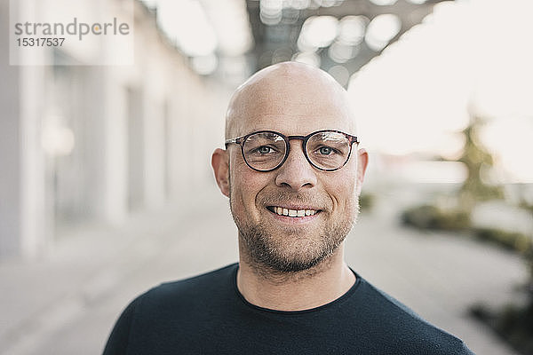Porträt eines lächelnden  kahlköpfigen Mannes mit Brille