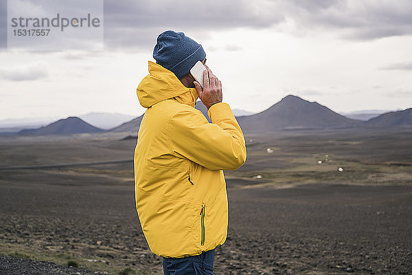Reifer Mann spricht auf seinem Smartphone im isländischen Hochland