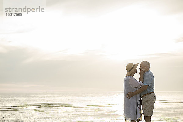 Älteres Ehepaar steht sich bei Sonnenuntergang am Strand gegenüber  Liepaja  Lettland