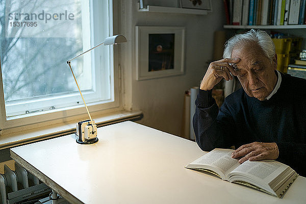 Älterer Mann liest zu Hause Buch