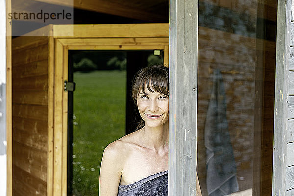 Porträt einer lächelnden Frau hinter einer Fensterscheibe in einer Sauna