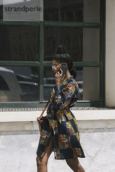 Porträt einer eleganten Frau in gemustertem Kleid  die mit dem Handy telefoniert