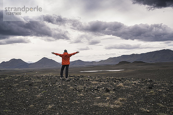 Junge Frau schaut mit ausgestreckten Armen auf die Aussicht  Hochlandregion  Island