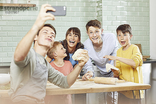 Einer  der Fotos von seiner Mutter und seinen Brüdern macht  die zu Hause Pizza zubereiten