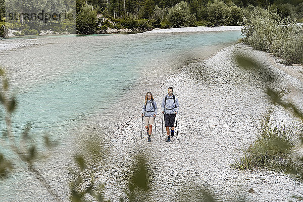 Junges Paar auf einer Wanderung zu Fuß am Flussufer  Vorderriss  Bayern  Deutschland