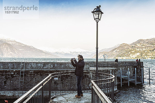 Mann mit Mobiltelefon beim Fotografieren am Comer See im Winter  Italien