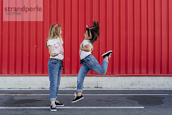 Schwestern springen auf die Strasse vor die rote Mauer