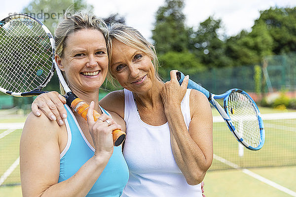 Porträt von zwei glücklichen reifen Frauen auf dem Rasenplatz eines Tennisclubs