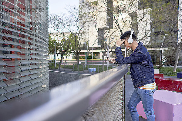 Junger Mann mit Kopfhörern schaut auf Handy  Barcelona  Spanien