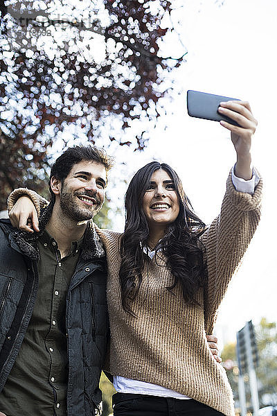 Porträt eines glücklichen Paares  das sich mit dem Handy selbstständig macht