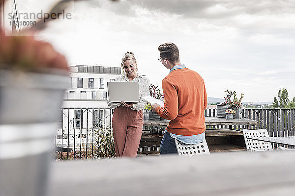 Gelegenheits-Geschäftsmann und -Frau mit Laptop treffen sich auf der Dachterrasse
