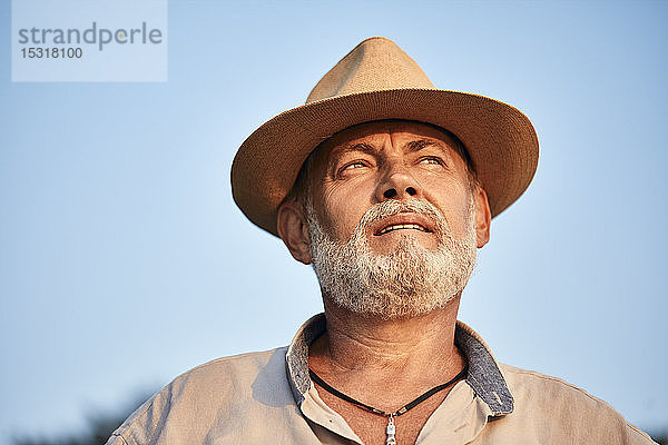 Porträt eines nachdenklichen älteren Mannes mit Sommerhut im Freien