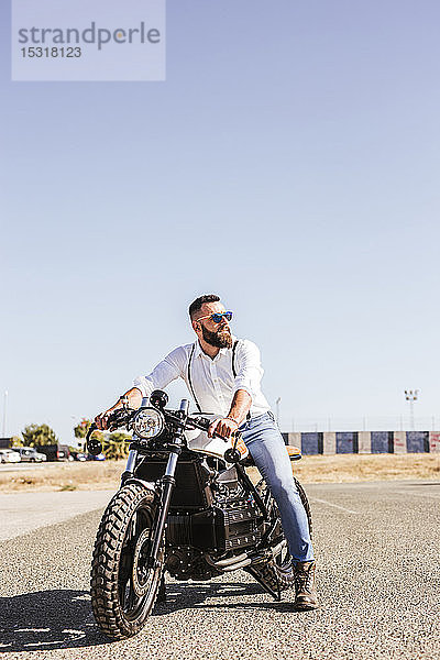 Porträt eines bärtigen Mannes  der auf seinem Motorrad sitzt