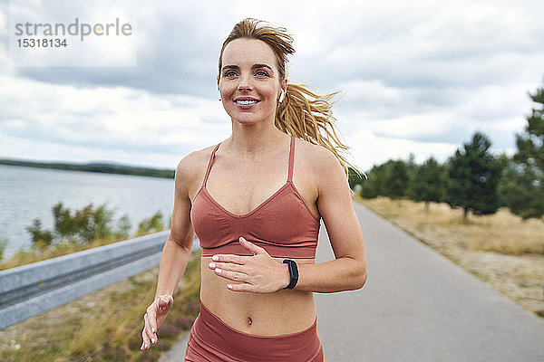 Porträt einer lächelnden athletischen Frau  die im Freien joggt