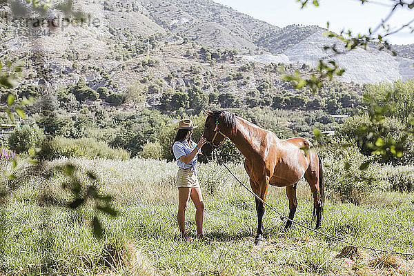 Junge Frau mit einem Pferd auf der Wiese