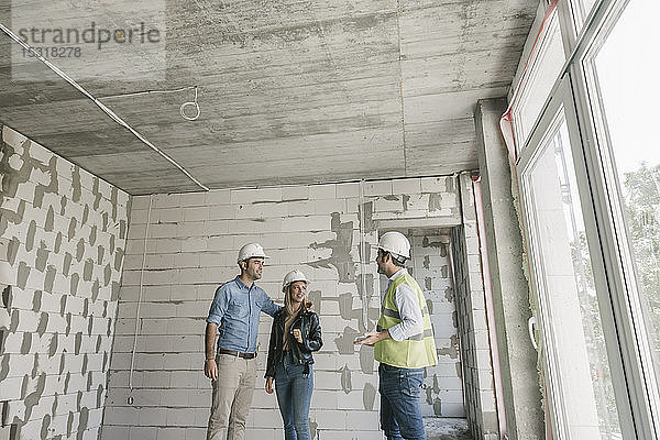 Architekt im Gespräch mit künftigen Eigentümern auf der Baustelle