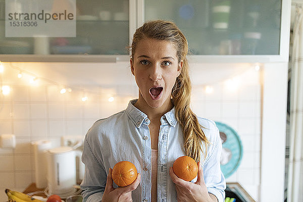 Porträt einer jungen Frau  die zu Hause Orangen hält