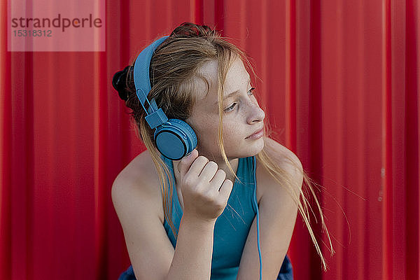 Mädchen mit Kopfhörern vor roter Wand