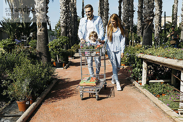 Familie kauft Pflanzen in einem Gartencenter mit der Tochter im Einkaufswagen