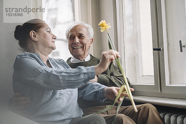 Glückliches älteres Ehepaar mit Blume zu Hause