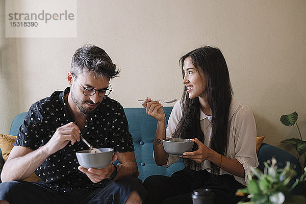 Junges Paar sitzt auf einer Couch in einem Café und frühstückt