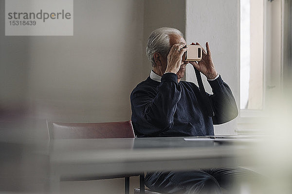 Älterer Mann zu Hause mit VR-Kartonbrille