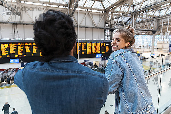 Glückliche junge Frau wartet mit ihrer Freundin am Bahnhof  London  UK