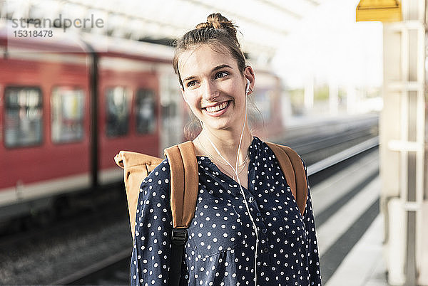 Porträt einer lächelnden jungen Frau am Bahnhof