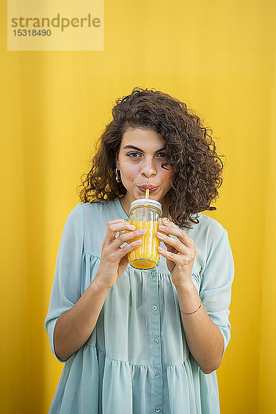 Porträt einer Saft trinkenden Frau  gelber Hintergrund