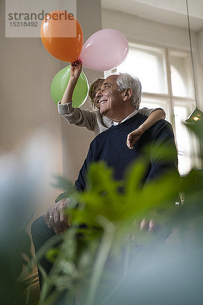 Glücklicher Großvater und Enkel  die zu Hause mit Luftballons spielen