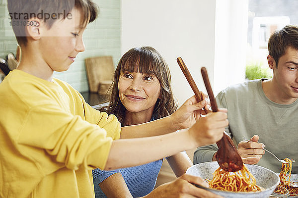 Mutter isst Spaghetti mit ihren Söhnen in der Küche