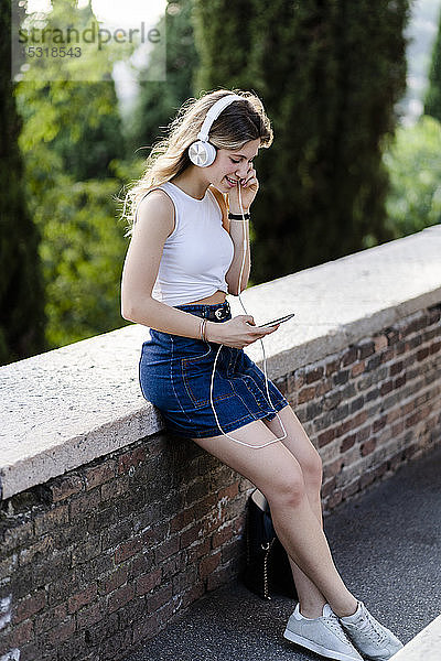 Junge Frau  die mit Kopfhörer und Smartphone Musik hört