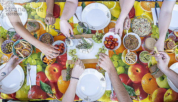 Gesundes vegetarisches Essen auf einem bunten Tisch mit Freunden  von oben