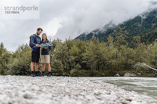 Junges Paar auf einer Wanderung am Flussufer beim Kartenlesen  Vorderriss  Bayern  Deutschland
