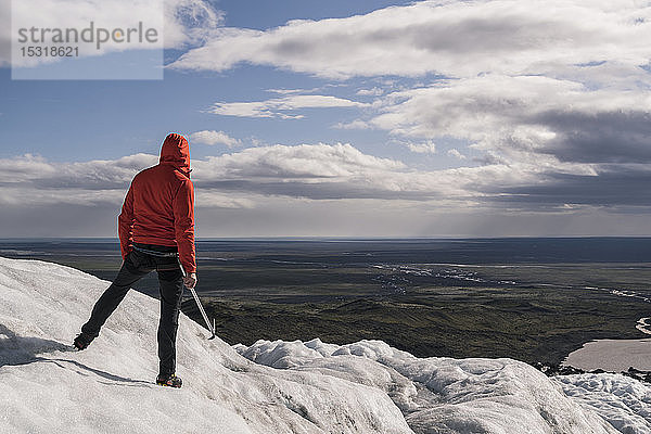 Erwachsener Mann steht im Skaftafell-Nationalpark auf dem Vatnajokull-Gletscher  Island  und hält einen Eispickel