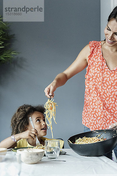 Mutter serviert Pasta-Mahlzeit für die am Esstisch sitzende Tochter