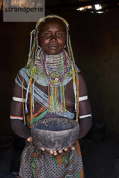 Porträt einer traditionellen Muhila-Frau  die in ihrem Haus steht und einen Topf hält  Congolo  Angola