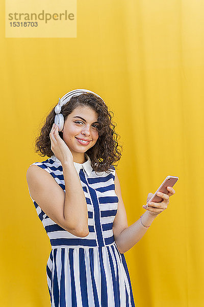 Porträt einer jungen Frau mit Kopfhörer und Smartphone