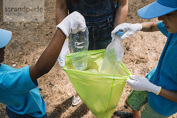 Nahaufnahme von ehrenamtlich arbeitenden Kindern beim Müllsammeln in einem Park