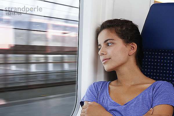 Allein im Zug reisendes Mädchen  das aus dem Fenster schaut