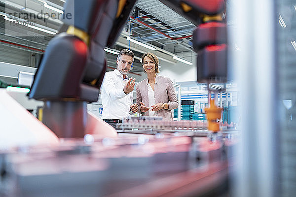 Geschäftsmann und Geschäftsfrau im Gespräch in einer modernen Fabrikhalle