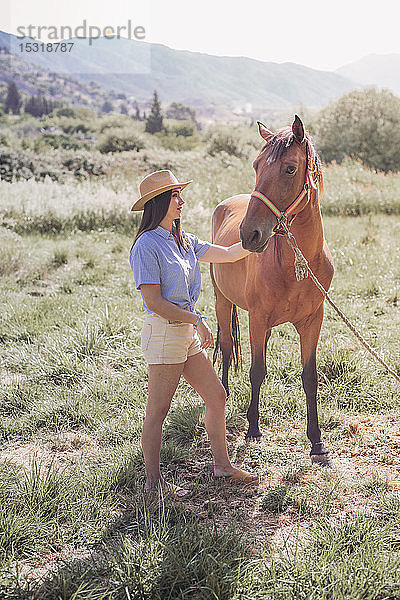 Junge Frau mit einem Pferd auf der Wiese