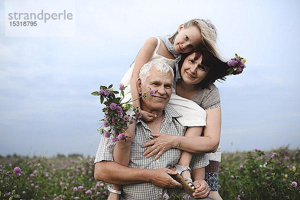 Porträt eines kleinen Mädchens und seiner Großeltern mit gepflückten Blumen in der Natur